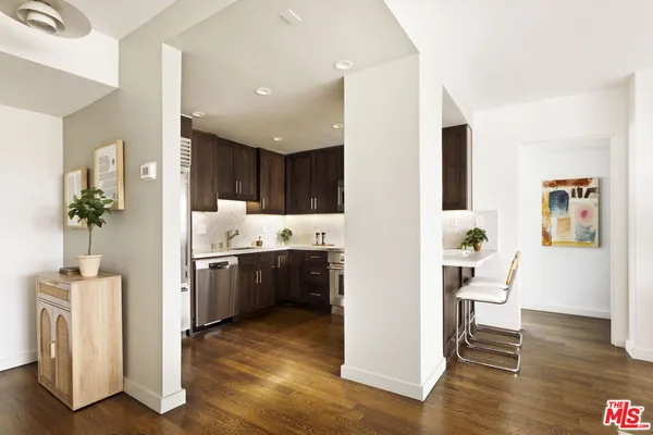 a living room with stainless steel appliances kitchen island granite countertop wooden floor and cabinets