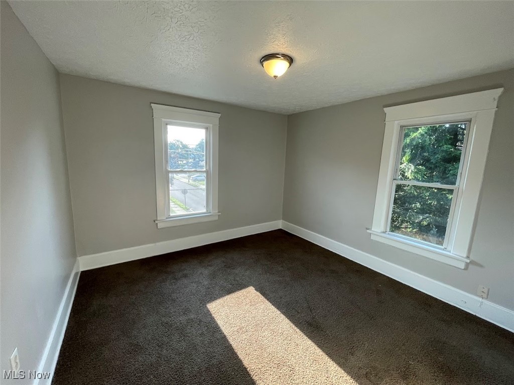 950 Avon Street Akron, OH 44310 - Photo 10 of 15 Unfurnished room with dark carpet, a textured ceiling, and baseboards