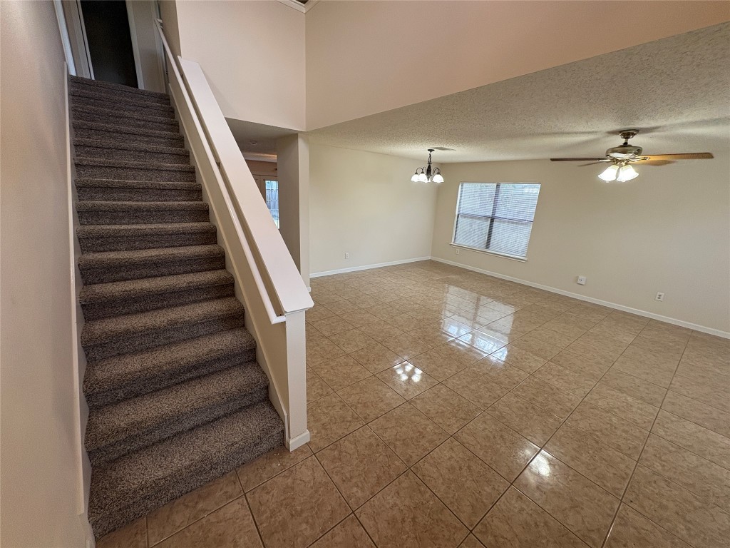 1367 Lakeside Loop Round Rock, TX 78665 - Photo 3 of 19 Stairway with a textured ceiling, tile patterned flooring, a chandelier, and a ceiling fan