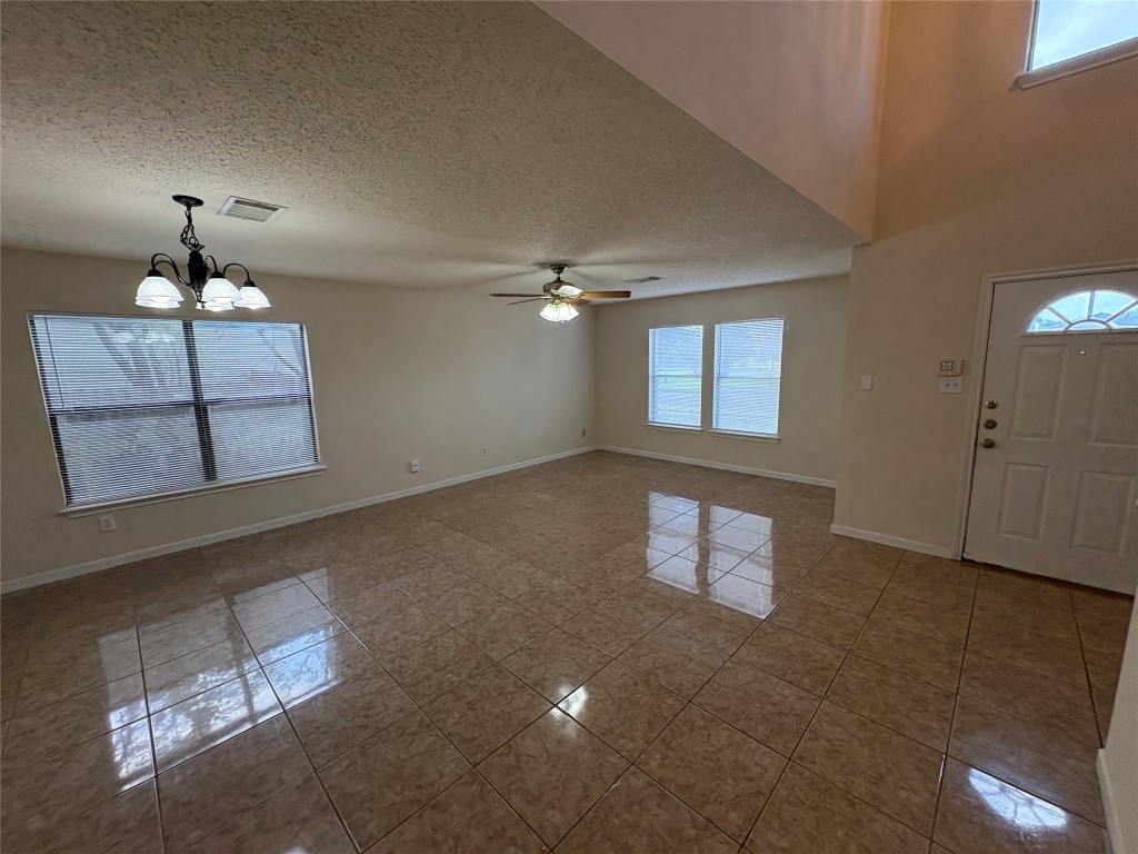 1367 Lakeside Loop Round Rock, TX 78665 - Photo 4 of 19 Foyer entrance featuring plenty of natural light, a chandelier, a textured ceiling, a ceiling fan, and dark tile patterned flooring