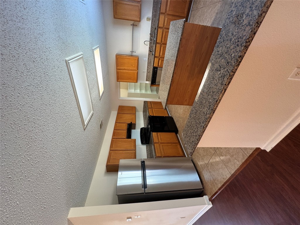 1367 Lakeside Loop Round Rock, TX 78665 - Photo 7 of 19 Kitchen featuring fridge, brown cabinetry, black stove, a textured ceiling, and a center island