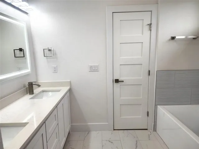 a bathroom with a granite countertop sink a mirror and a bathtub