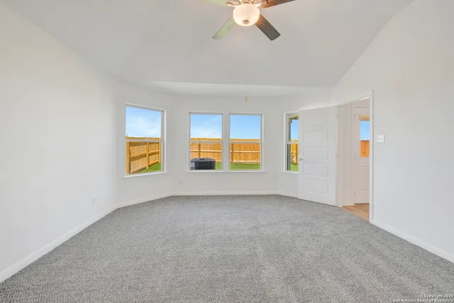 an empty room with windows and chandelier fan