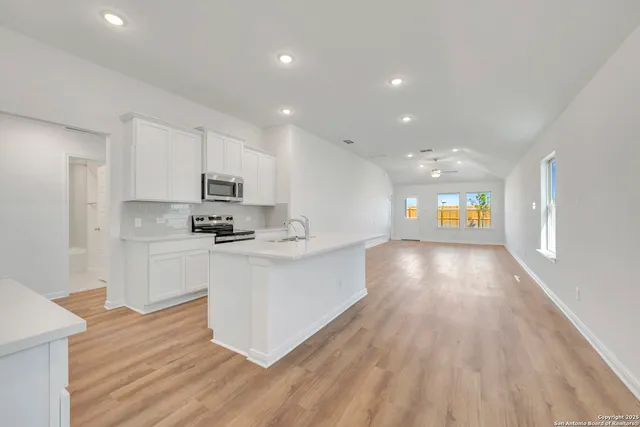a view of kitchen with cabinets stainless steel appliances and wooden floor