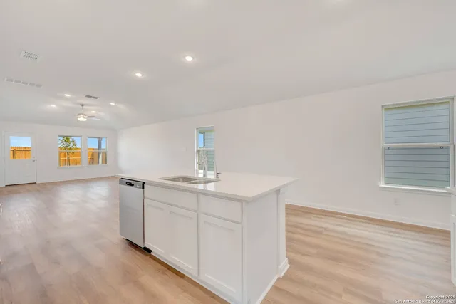 a view of a kitchen with a sink and dishwasher with wooden floor