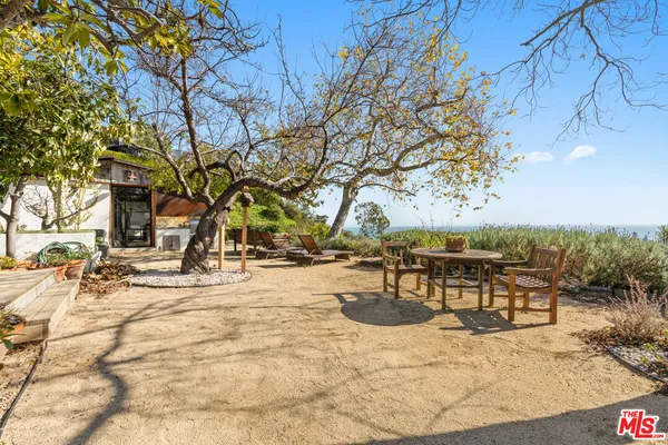a view of a patio with table and chairs potted plants with wooden floor and fence