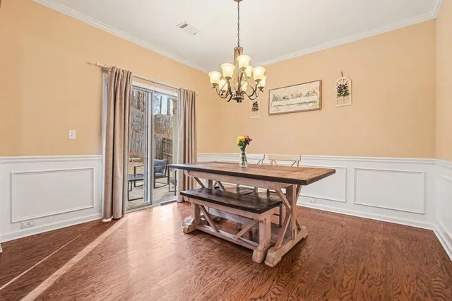 a dining room with wooden floor a chandelier a wooden table and chairs