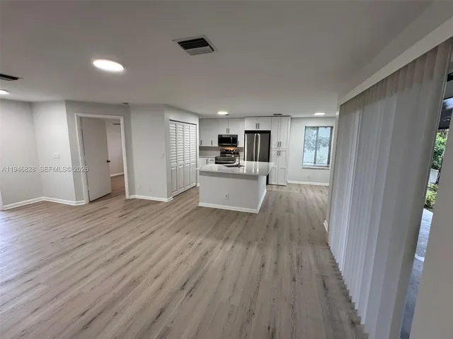 a view of a kitchen from a hallway with wooden floor and a kitchen space