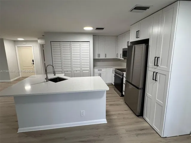 a kitchen with stainless steel appliances a refrigerator sink and wooden floor