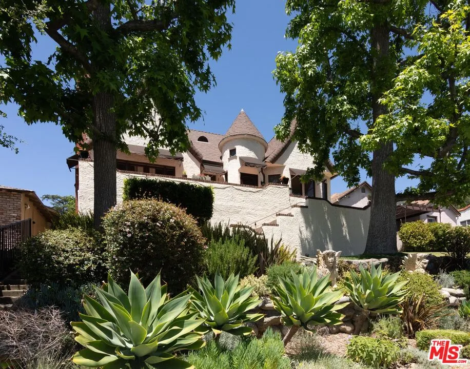 a front view of a house with a yard and covered with trees