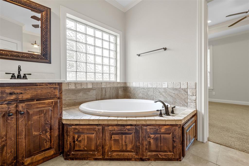 144 Ellis Farm Road Hewitt, TX 76643 - Photo 25 of 36 Built-in soaking tub with a tiled surround and dark wood cabinetry