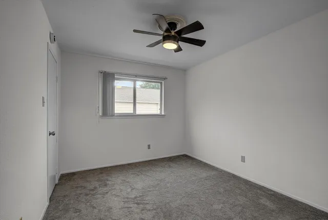 an empty room with a ceiling fan and window
