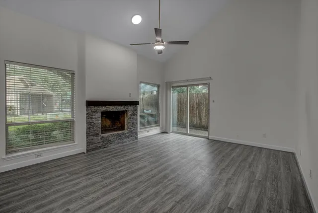 an empty room with wooden floor fireplace and windows