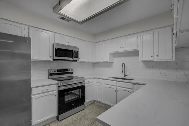 a kitchen with cabinets stainless steel appliances and a counter space
