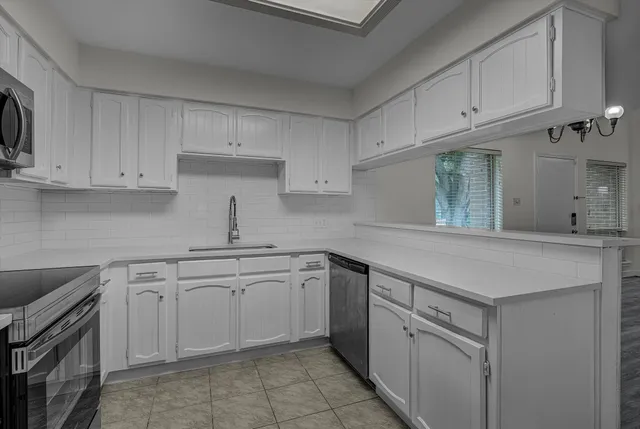 a kitchen with white cabinets stainless steel appliances and sink