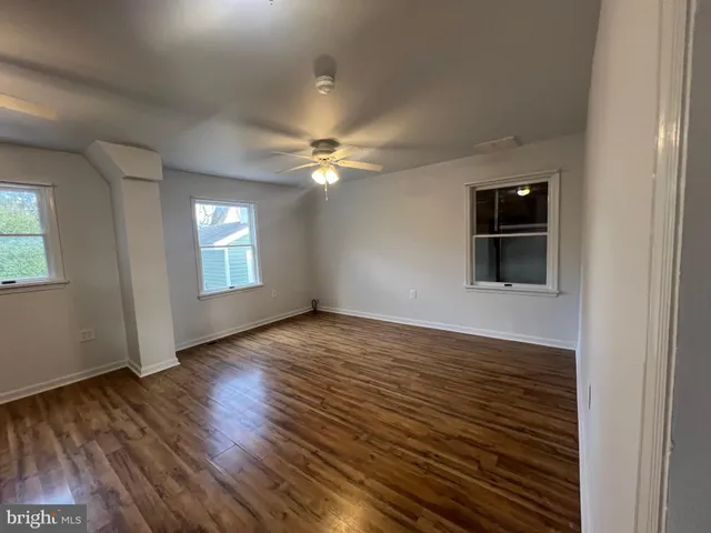 a view of an empty room with window and wooden floor