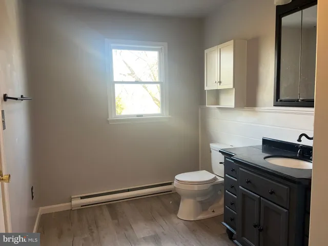 a bathroom with a granite countertop sink a toilet and a window