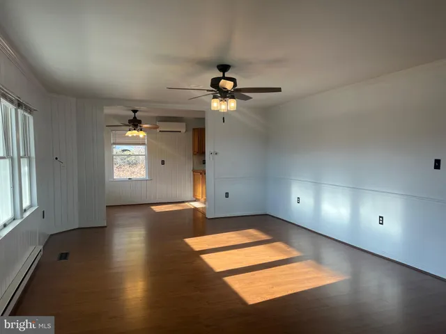 an empty room with windows and ceiling fan