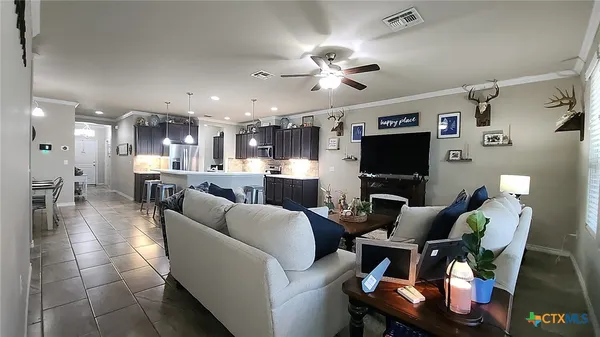 a living room with furniture a flat screen tv and kitchen view