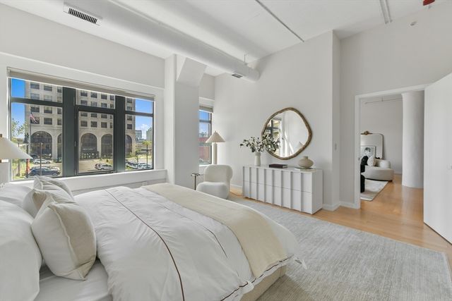 a spacious bedroom with a bed a large window and a chandelier