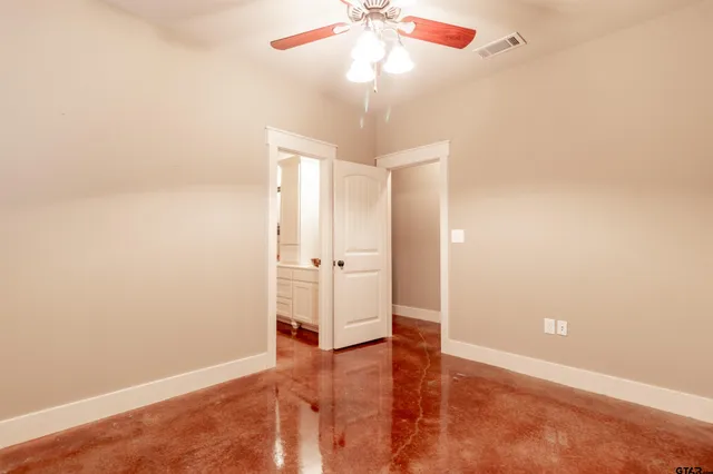 an empty room with a chandelier fan and windows