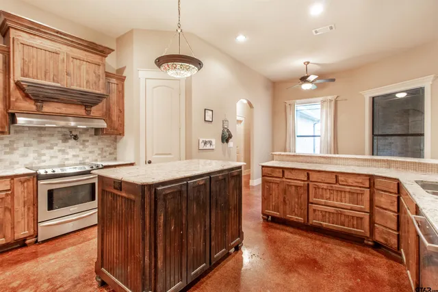 a kitchen with granite countertop a stove top oven and cabinets