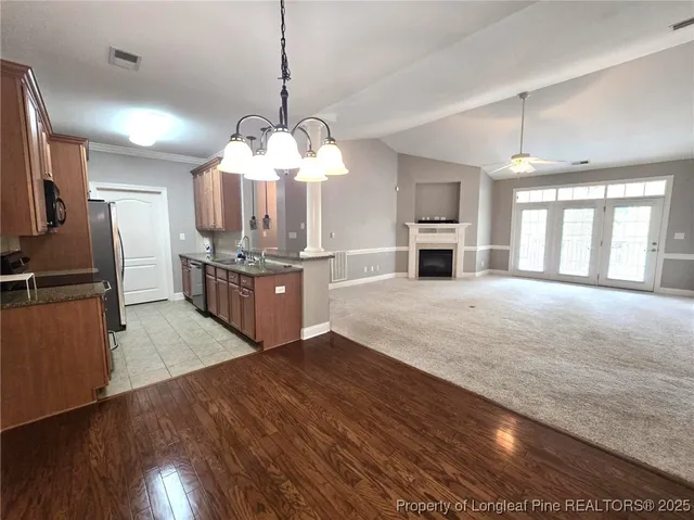 a open kitchen with stainless steel appliances granite countertop a refrigerator a stove and a wooden floors