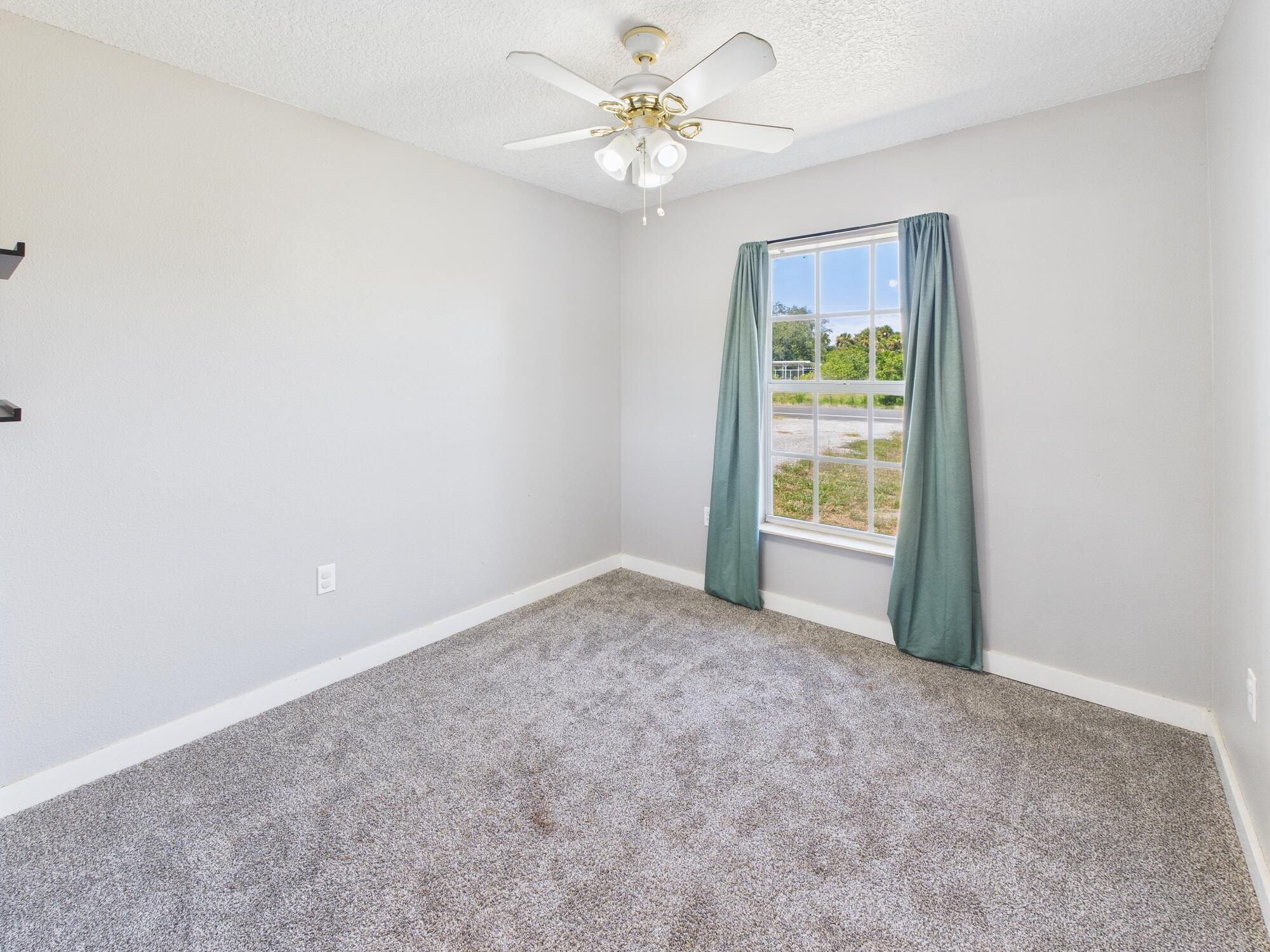 6504 Southeast 86th Boulevard Okeechobee, FL 34974 - Photo 21 of 38 an empty room with windows and fan