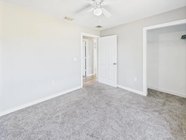an empty room with a ceiling fan and a window