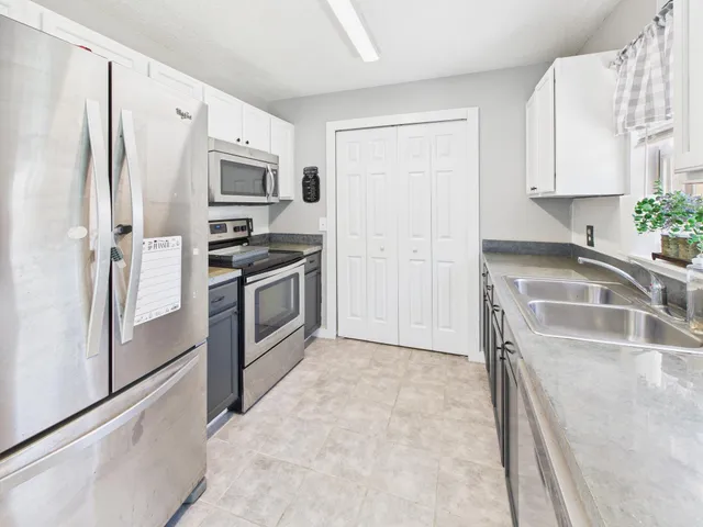 a kitchen with stainless steel appliances granite countertop a refrigerator a stove and a sink with wooden floor