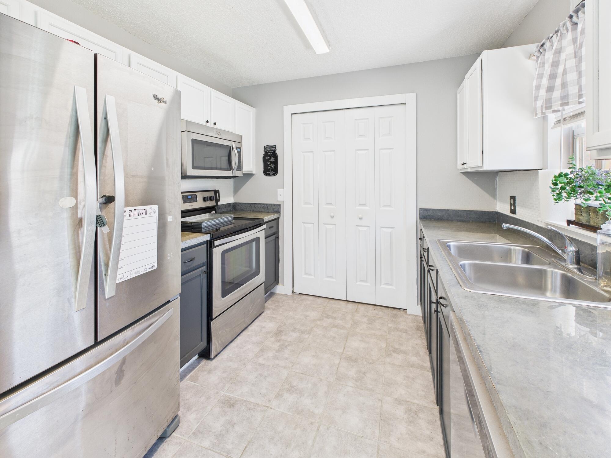 6504 Southeast 86th Boulevard Okeechobee, FL 34974 - Photo 7 of 38 a kitchen with stainless steel appliances granite countertop a refrigerator a stove and a sink with wooden floor