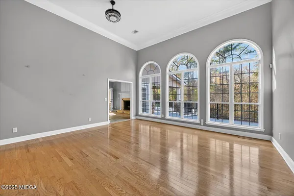 a view of an empty room with wooden floor and a window