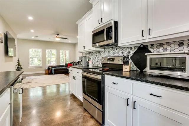 a kitchen with stainless steel appliances granite countertop a stove a sink and a microwave