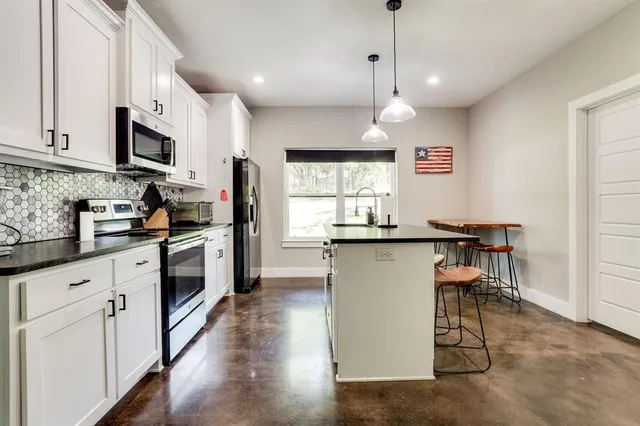 a kitchen with stainless steel appliances granite countertop a refrigerator a stove a sink dishwasher and a microwave with wooden floor