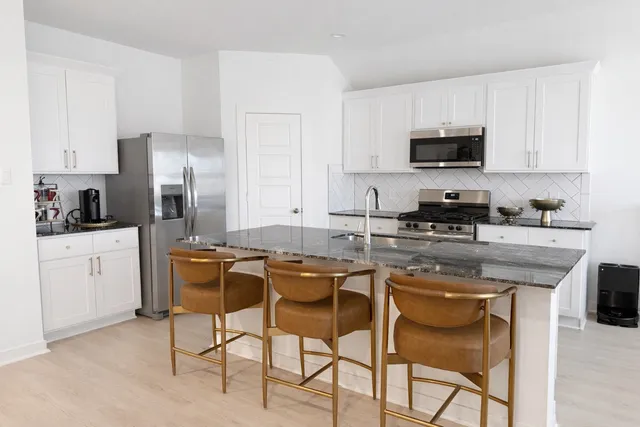 a kitchen with stainless steel appliances granite countertop a sink a stove a refrigerator and cabinets