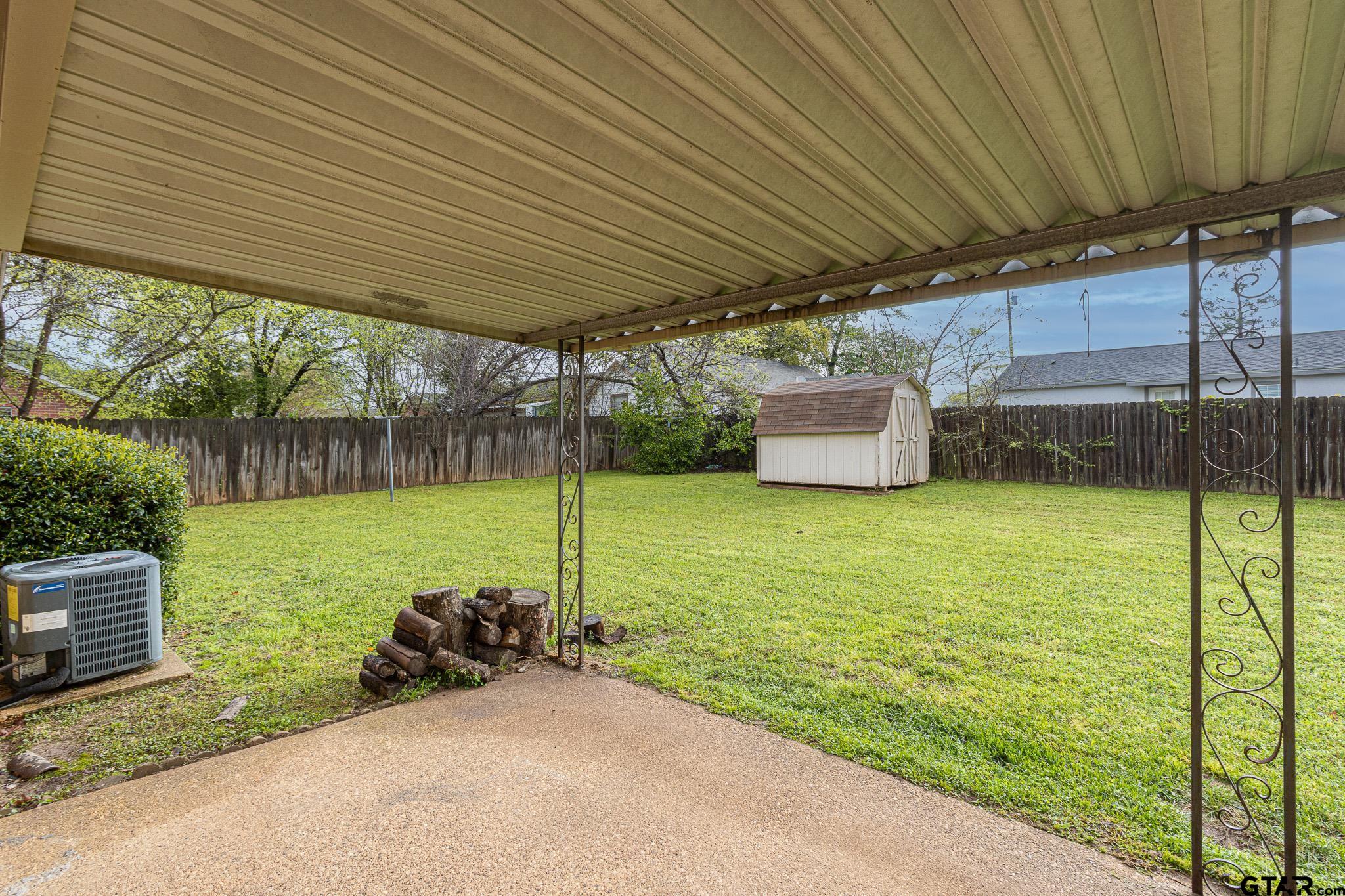 1202 Ridgeview Drive Tyler, TX 75701 - Photo 15 of 20 a view of a backyard with table and chairs under an umbrella