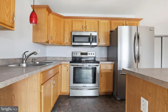 a kitchen with stainless steel appliances granite countertop a refrigerator a stove a sink and a microwave