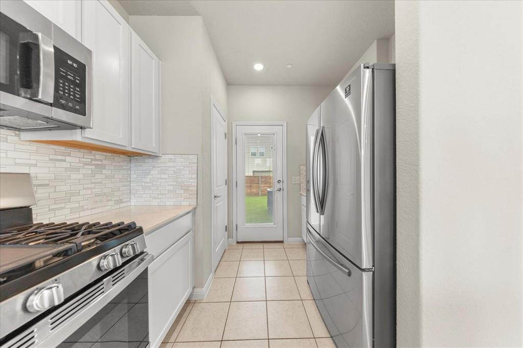 9015 Cattle Baron Path, Unit 1502 Austin, TX 78747 - Photo 18 of 31 Kitchen with stainless steel appliances, white cabinetry, light tile patterned flooring, recessed lighting, and tasteful backsplash