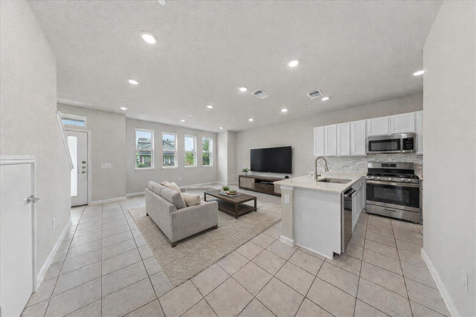 9015 Cattle Baron Path, Unit 1502 Austin, TX 78747 - Photo 30 of 31 Kitchen featuring stainless steel appliances, white cabinets, open floor plan, a peninsula, and backsplash
