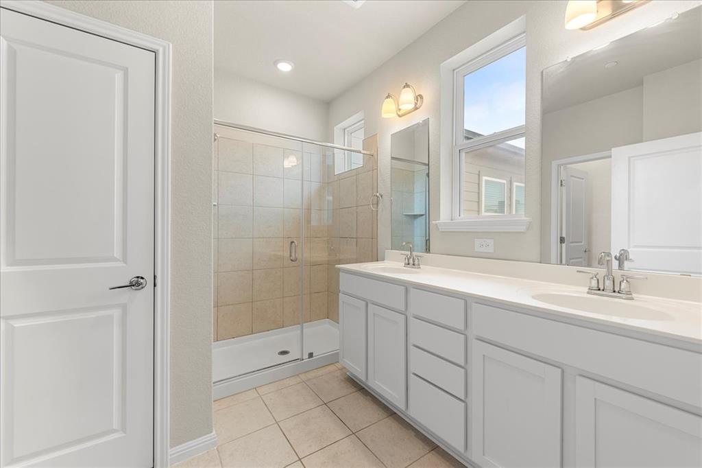 9015 Cattle Baron Path, Unit 1502 Austin, TX 78747 - Photo 7 of 31 Bathroom with double vanity, a shower stall, and light tile patterned floors