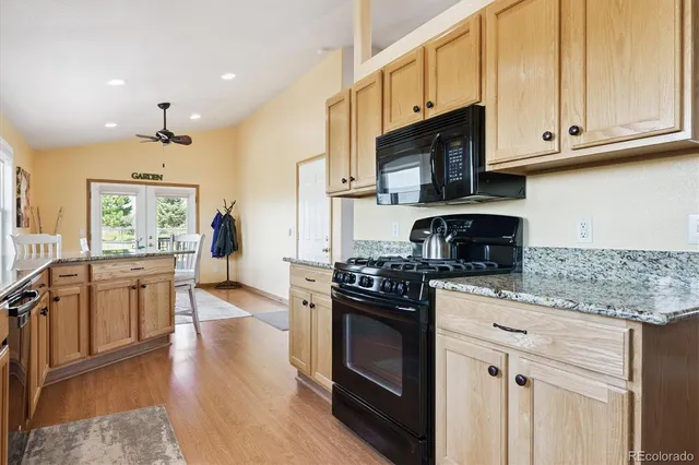 a kitchen with stainless steel appliances granite countertop a stove top oven a sink dishwasher and a microwave oven with wooden floor