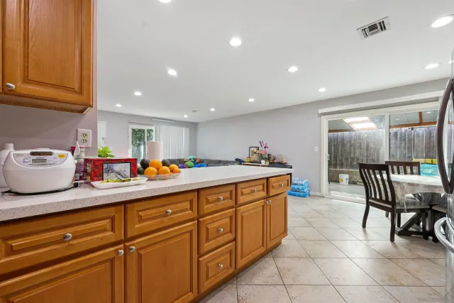 a kitchen with stainless steel appliances kitchen island granite countertop a refrigerator a sink a dining table and chairs