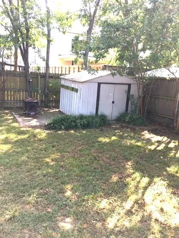 a view of a backyard with a large tree and wooden fence