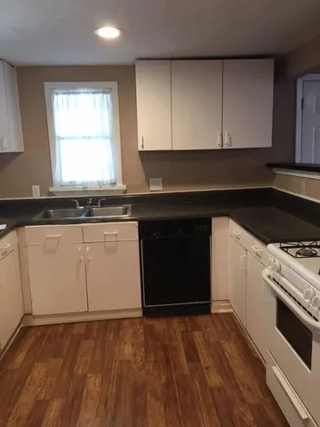 a kitchen with granite countertop a stove a sink and a microwave