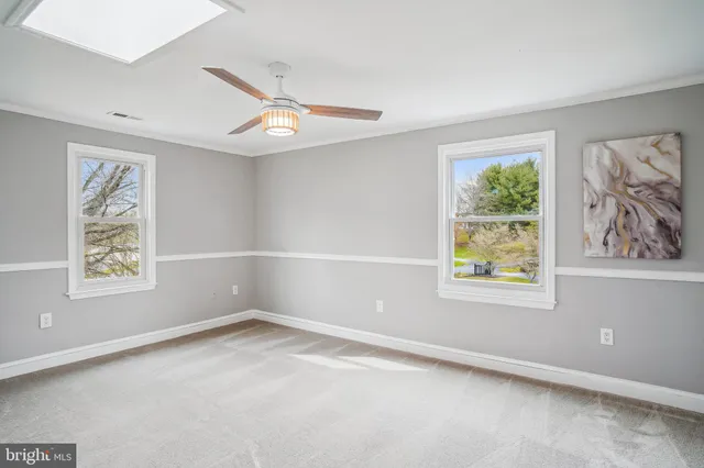 an empty room with windows and ceiling fan