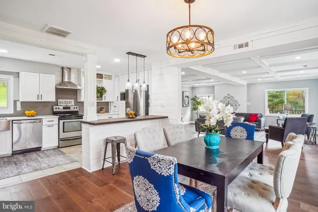 a kitchen with stainless steel appliances granite countertop a dining table chairs stove and a refrigerator