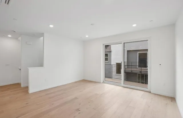 a view of an empty room with wooden floor and closet
