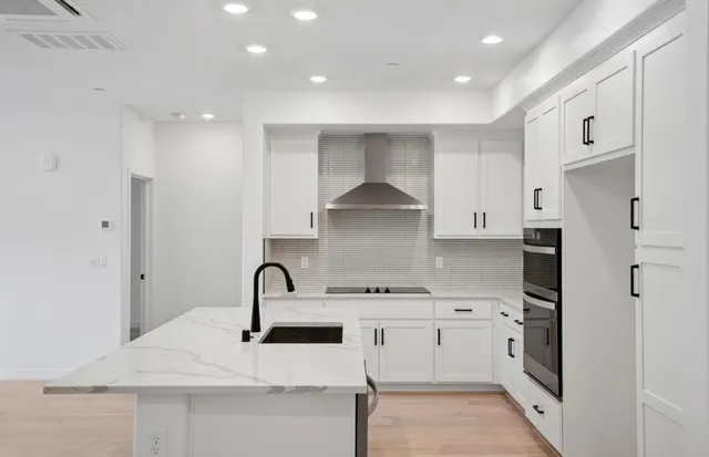 a kitchen with white cabinets and sink