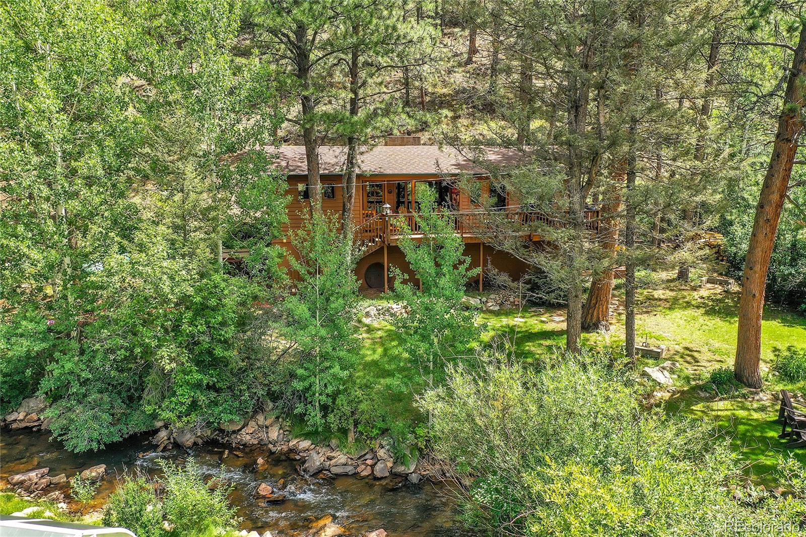14432 South Elk Creek Road Pine, CO 80470 - Photo 5 of 50 a backyard of a house with table and chairs under an umbrella