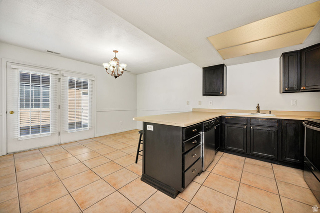 2 West 1780 North Logan, UT 84341 - Photo 8 of 24 Kitchen with a peninsula, a kitchen bar, light countertops, dark cabinets, and a textured ceiling